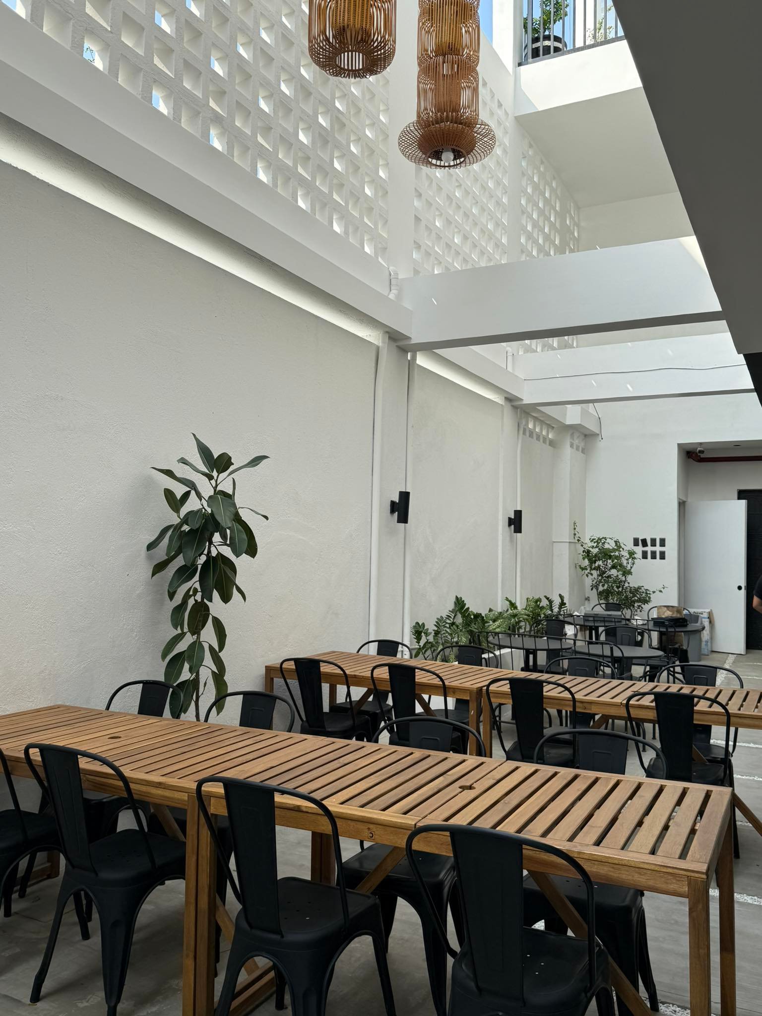 Bright open-air atrium seating area with rattan lamps at 2nd Home